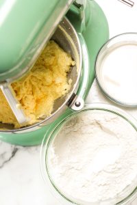 Mixer bowl with combined batter next to flour and milk.