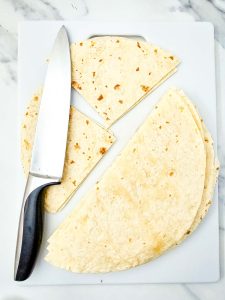 Flour tortillas cut into triangles with a knife for enchilada casserole.