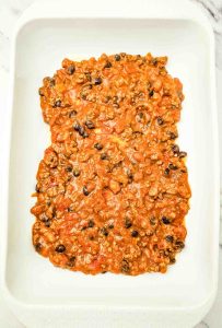 Enchilada casserole filling spread in a white baking dish.