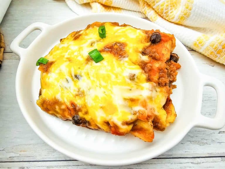 Close-up of enchilada casserole slice with melted cheese, ground beef, and black beans.