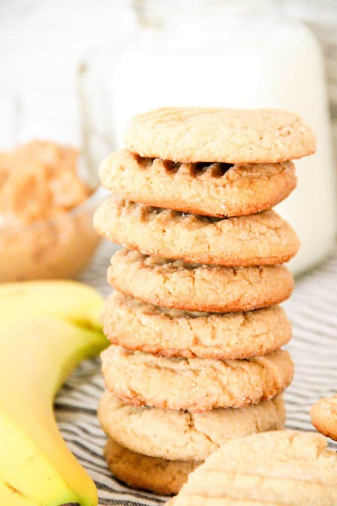 Peanut Butter Banana Cookies stacked with milk and bananas behind.