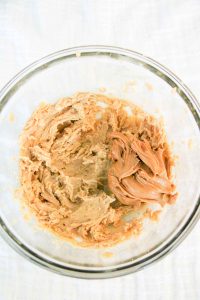 Peanut butter added to mixture in a bowl for Peanut Butter Banana Cookies.