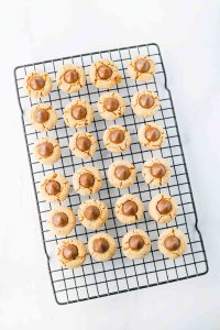 Peanut butter blossom cookies topped with chocolate kisses cooling on a wire rack.