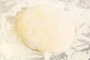Soft dough ball resting on a floured surface, lightly dusted with flour.