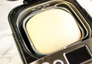 Smooth dough ball resting inside a bread machine pan.