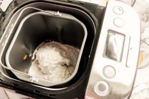Bread machine pan with flour and ingredients added, ready for mixing.