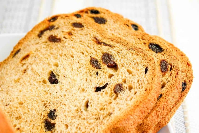 Close view of a loaf of cinnamon raisin bread with slices showing raisins inside.