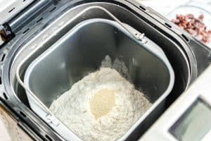 Bread machine pan filled with flour and yeast ready for mixing.